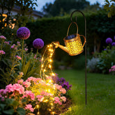 Solar powered vintage kettle garden light with cascading LED water flow effect glowing on outdoor patio at night
